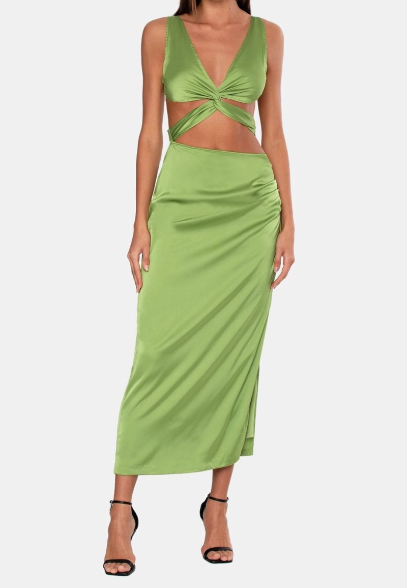 Groene satijnen jurk met een diepe halslijn en gedraaide uitsnijdingen. Lange, aansluitende silhouet; ruches aan de zijkant en sandalen met bandjes.