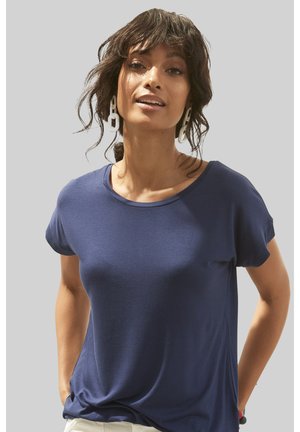 Navy blue short-sleeve t-shirt with a round neckline and smooth texture, worn with light-colored pants and large white earrings.