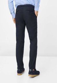 Donker marineblauwe chino's met een rechte pasvorm, van katoen, met subtiele achterzakken. Gecombineerd met donkere suède schoenen en een lichtblauw shirt.