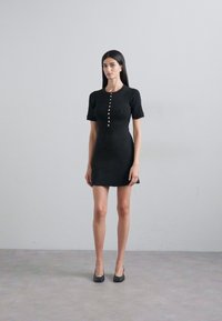 Black knitted dress with short sleeves, round neckline, and a row of buttons down the front. Smooth texture, fitted silhouette, mid-thigh length.