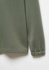 Manche de sweat-shirt vert clair avec une texture lisse, présentant un poignet froncé et un ourlet cousu pour un effet ajusté.
