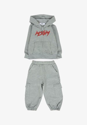 Szara dziecięca dwuczęściowa odzież składająca się z bluzy z zamkiem i kapturem, z czerwonym napisem "MSGM" oraz spodni z elastycznym pasem i mankietami, które mają kieszenie.