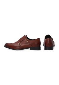 Braune Lederschuhe mit strukturiertem Finish, ausgestattet mit zwei Riemen und subtilen Brogue-Details. Glatte schwarze Sohle und runde Zehenform.