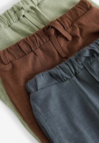 Trois paires de pantalons en vert olive, marron et gris foncé. Chacune est dotée d'une taille élastique avec un cordon de serrage. Texture de tissu douce.