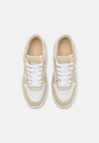 Sneaker beige e bianche con dettagli perforati, colletto imbottito, lacci bianchi e logo metallico "GUESS" di lato.