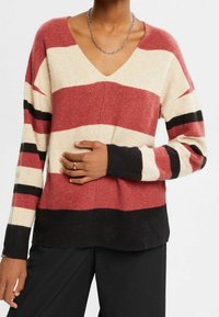 Langärmeliger Pullover mit V-Ausschnitt und horizontalen Streifen in Rot, Creme und Schwarz. Weicher, strukturierter Stoff mit gerippten Bündchen und Saum.