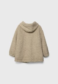 Beige fleece jacket with a soft, textured exterior. Features a hood, wide sleeves, and a relaxed fit with no visible closure.