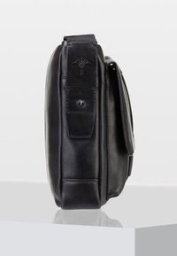 Svart läder crossbody-väska med framficklock och justerbar axelrem, visad från sidan på en vit yta.