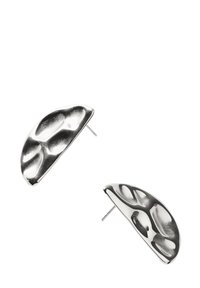 Un paio di orecchini a stud a forma di mezza luna in argento, con una superficie testurizzata e irregolarmente incavata e spuntoni dritti per il fissaggio.