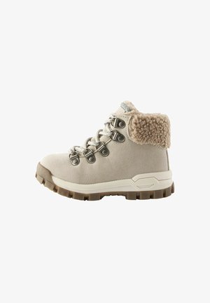 Scarponcino da trekking beige con colletto in pelliccia, occhielli in metallo e lacci bianchi. Suola in gomma texture per aderenza e stabilità. Design con tacco piatto.