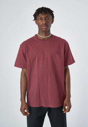 Bordeauxfarbendes Baumwoll-T-Shirt mit kurzen Ärmeln, Rundhalsausschnitt und einem kleinen Vogel-Logo, das in einem dunkleren Farbton auf der Brust gestickt ist. Glatte Textur.