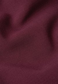Tessuto bordeaux, texture liscia, leggermente elasticizzato, con un motivo a maglia fine, uniformemente tessuto. Adatto per abbigliamento o tappezzeria.