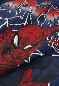 Czerwony i niebieski materiał bawełniany z grafiką Spider-Mana i wzorem pajęczyny, podkreślający odważne linie i żywe kolory w zabawnym układzie.