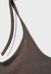Haut marron sans manches avec fines bretelles, coutures détaillées le long des bords, présenté sur un fond clair uni.
