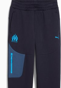 Marineblauwe sweatpants met een elastische tailleband, voorzien van een blauwe zakkenpaneel, een ritszak en lichtblauwe logo's aan de voorkant.