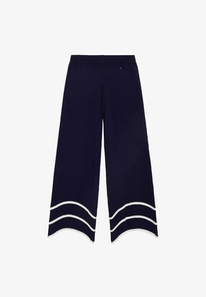Pantalones anchos azul marino con dobladillos ondulados, con dos rayas blancas onduladas cerca de la parte inferior de cada pierna.