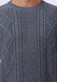 Pull en tricot gris avec motifs texturés, y compris des designs en cable et en diamant, avec un col rond côtelé.