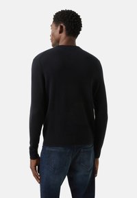 Marineblauer Strickpullover mit rundem Ausschnitt, langen Ärmeln und gerippten Bündchen. Trägt man über blauen Jeans und zeigt ein klassisches, lässiges Design.