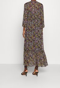 Robe longue en tissu noir transparent avec un motif floral multicolore, dotée de manches trois-quarts et d'un ourlet à volants à plusieurs niveaux.
