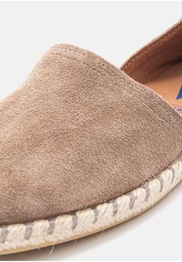 Brown suede slip-on espadrille featuring a woven jute sole, rounded toe, and minimal stitching details along the edge.