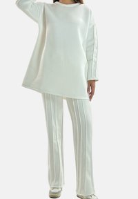 Witte oversized sweatshirts met lange mouwen en een ronde hals, gecombineerd met bijpassende gestreepte wijde broekspijpen. Zachte stoftextuur.