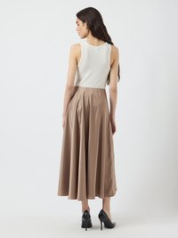 White ribbed tank top paired with a flowy, knee-length, light brown satin skirt and black high-heeled shoes, viewed from the back.