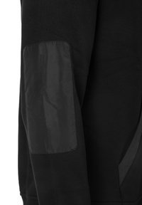 Manche longue noire avec un patch de coude rectangulaire et lisse cousu sur le côté extérieur de la manche.