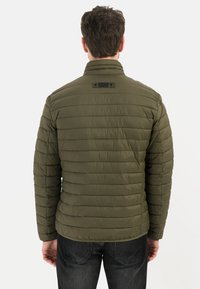 Oliven grøn dunjakke med vandret syninger, stående krave og forstærket flapdetalje på bagsiden. Let og polstret design.