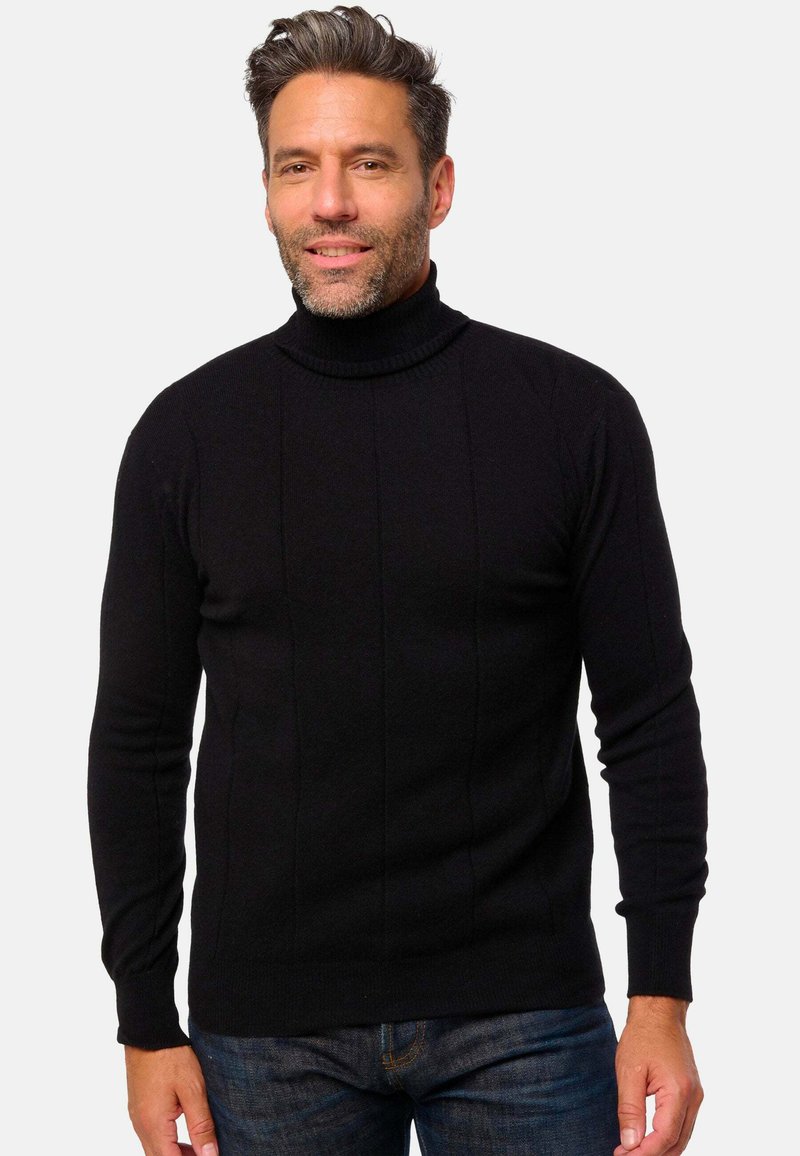 Schwarzer Rollkragenpullover mit geripptem Kragen und vertikalen Streifen; lange Ärmel und figurbetontes Design, kombiniert mit dunkelblauen Jeans.