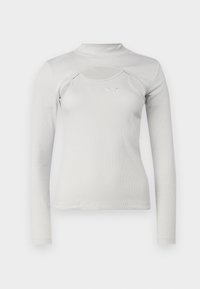 Tricou deschis la culoare, cu mânecă lungă, textură ribbed, guler înalt, detaliu decupat și un mic logo brodat pe piept.