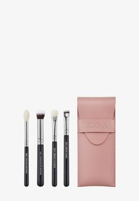 Set di quattro pennelli per il trucco con manici neri e ferule argentate, racchiusi in una morbida custodia in pelle rosa con marchio in rilievo.