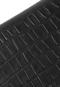 Materiale in pelle nera con un motivo in pelle di coccodrillo. La texture presenta squame in rilievo e aree lisce, mettendo in risalto la qualità tattile.