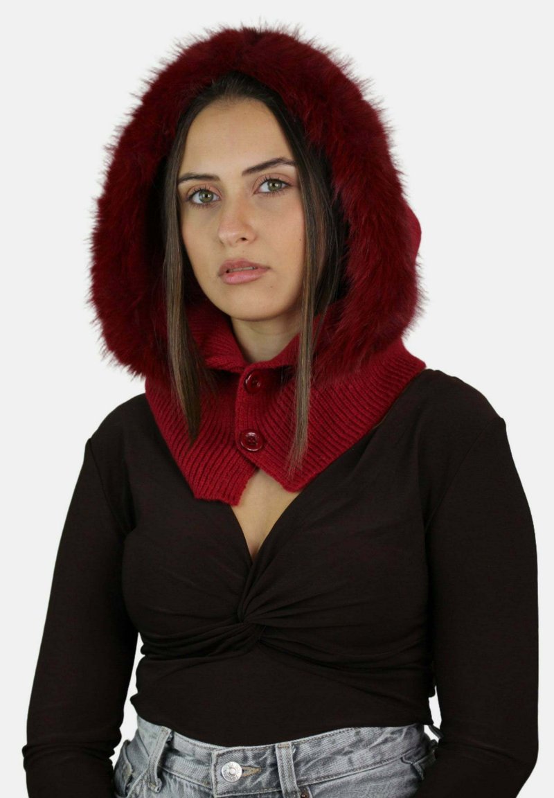 Cappuccio rosso lavorato a maglia con bordo in pelliccia sintetica e due bottoni decorativi, abbinato a una maglietta scura e pantaloncini di jeans a vita alta. Design moderno e testurizzato.