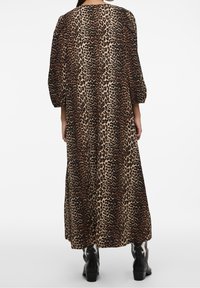 Vestido largo de estampado de leopardo con manchas marrones y negras sobre un fondo beige; cuenta con mangas abullonadas y un corte relajado.