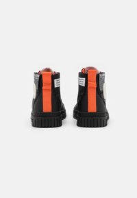 Stivali neri alla caviglia con una striscia di accentuazione arancione, suola in gomma, tessuto testurizzato e un patch rotondo con logo sul retro.