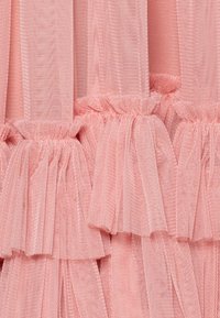 Rosa tuletyg med lager av volanger och en mjuk struktur, samlad upptill med elastik. Lätt och luftigt utseende.