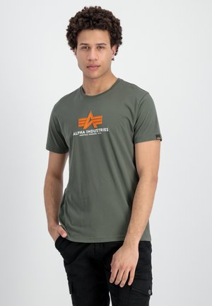 Camiseta de algodón color verde olivo con un logo gráfico naranja en el pecho, cuello redondo, mangas cortas y dobladillo recto.