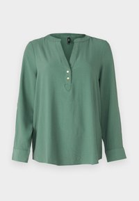 Blusa lunga verde con maniche a lunghezza intera e scollatura a V, tre bottoni dorati davanti e orlo leggermente curvo. Tessuto liscio e morbido.