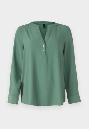 Roheline pikkade varrukatega pluus V-kaelusega, ees kolm kuldset nööpi ja kergelt kaarduv hemline. Sile ja pehme kangas.