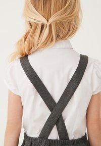 Biała koszula krótki rękaw z kołnierzykiem, z szarymi krzyżującymi się paskami z tyłu i teksturowanym materiałem.