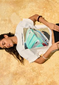 T-shirt en coton blanc avec un motif graphique d'un véhicule turquoise, accompagné du texte "PRÊT POUR UNE BALADE ÉCLATANTE ?" en noir au-dessus de l'image.