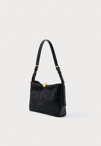 Geantă de mână neagră din piele netedă, cu față texturată din piele cu păr. Dispune de o închizătoare circulară aurie și o curea de umăr reglabilă.