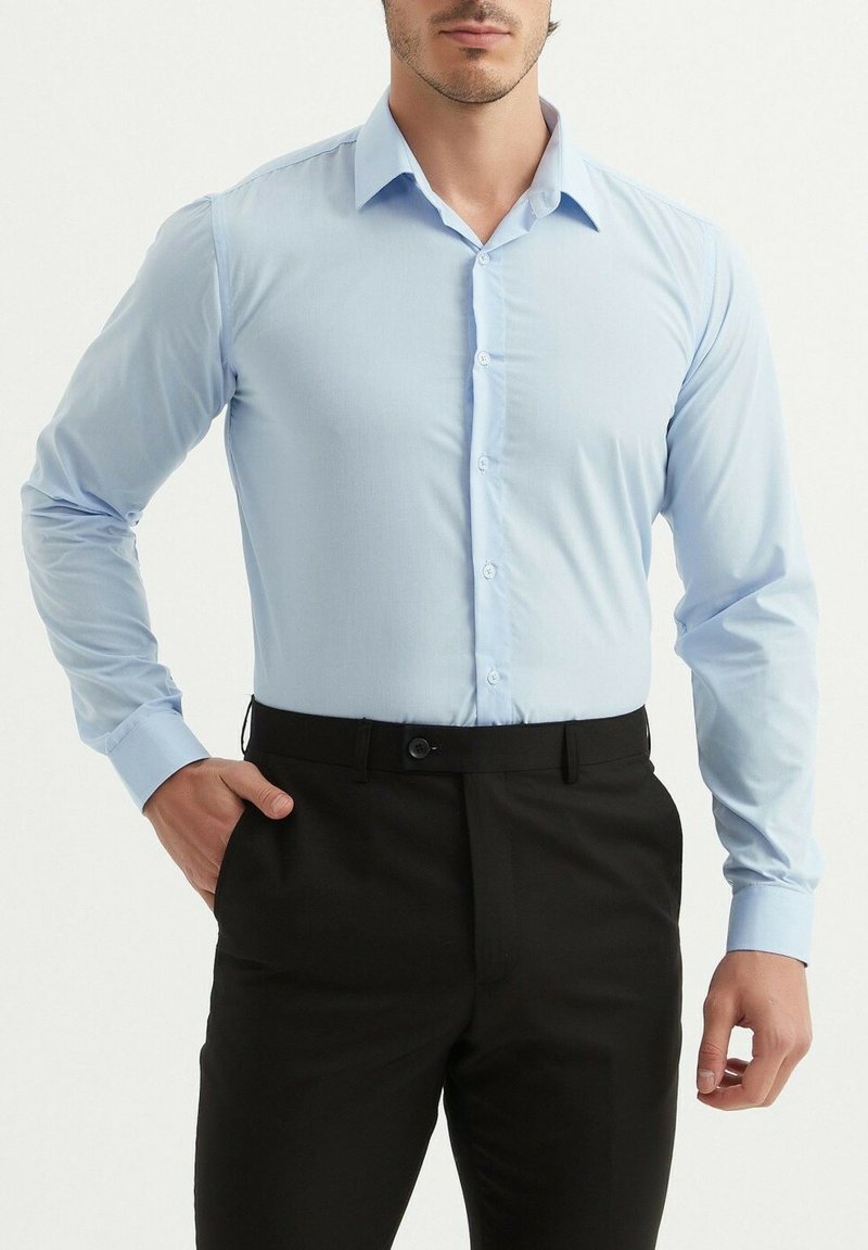 Chemise à manches longues bleu clair avec un design à boutons et un col pointu, portée avec un pantalon noir. Tissu lisse, silhouette ajustée.