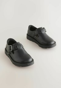 Schwarze Leder Schuhe mit strukturiertem Finish, ausgestattet mit einem Riemen und einer Schnalle, runder Zehenpartie und einer dicken, robusten Sohle.