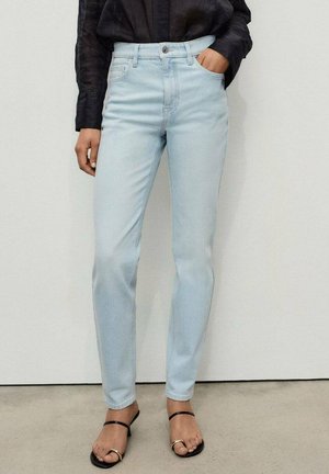 Ljusblå rakbenade jeans i denim, med hög midja, femficksdesign och knappstängning framtill. Svarta sandaler med remmar visas.