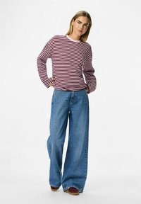 Bordový a bílý pruhovaný dlouhý rukáv tričko s růžovým výstřihem, spárované s volnými modrými džínami a červenými botami.