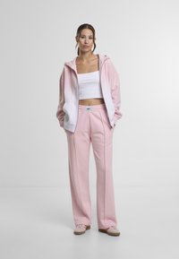 Pink hoodie med en hvid gradient, parret med lyserøde sweatpants. Blødt stof, afslappet pasform og elastisk talje med logo detaljer.