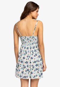 Blumendruck-Sommerkleid mit dünnen Trägern, gerafftem Oberteil und ausgestellt Rock. Die Farben umfassen Hellblau, Grün, Rosa und Marineblau. Weiche Stofftextur.