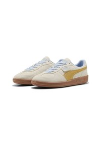 Puma-tennarit vaaleasta mokasta keltaisilla yksityiskohdilla, vaaleansinisillä nauhoilla ja ruskealla kumipohjalla. Varustettu tekstuuripinnalla ja logoyksityiskohdalla.