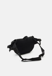 Svart mesh midjeväska med justerbar rem och spänne liggande platt på en vit bakgrund.